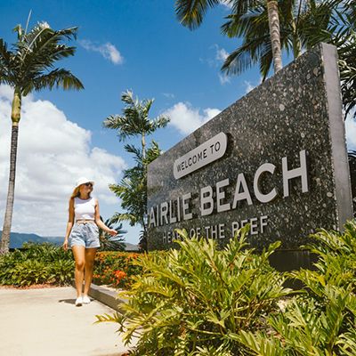 girl walking by Airlie Beach sign