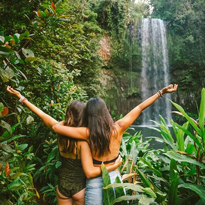 girls posing in front of a waterfall in the rainforest