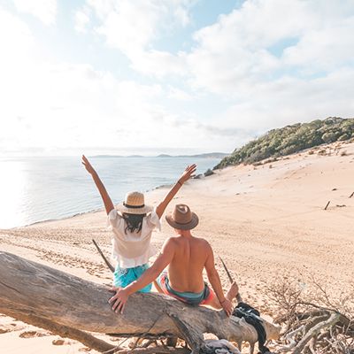 couple posing on sand dunes overlooking the ocean