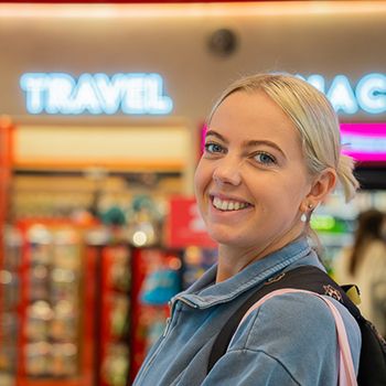 A woman with blonde hair in a travel shop with a backpack