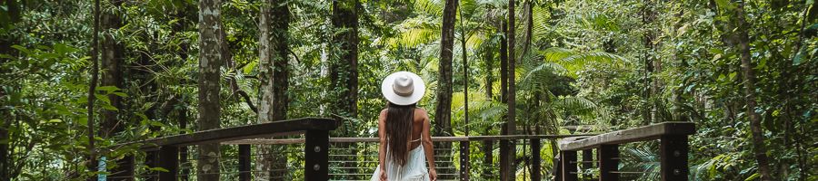girl walking down a boardwalk in the rainforest