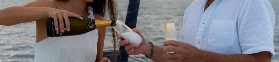 A couple pouring champagne on a sunset sail around Port Douglas