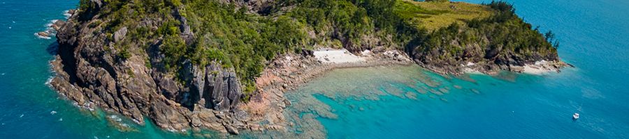 An island in the Whitsundays with blue reefs and waters
