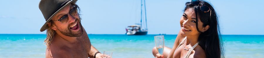couple smiling with champagne on whitehaven beach