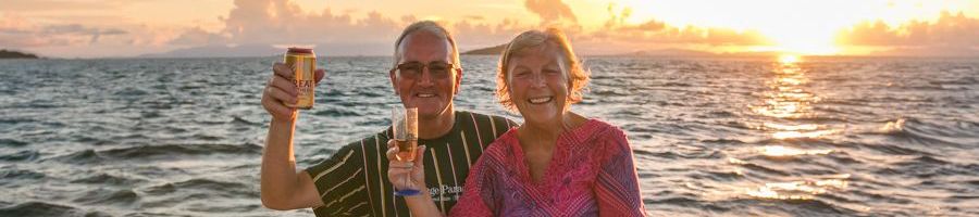 couple raising drinks on a boat at sunset