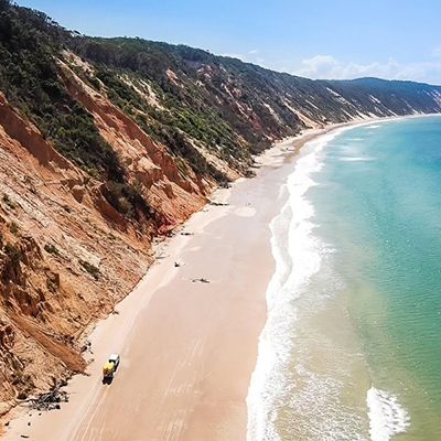 rainbow cliffs next to beach and turquoise ocean in Rainbow Beach