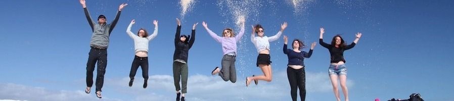 A group of friends jumping up in the air on the beach