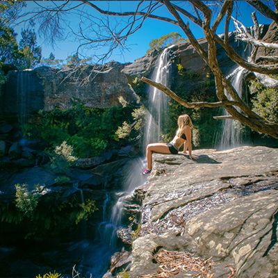 girl sitting next to a waterfall in the blue mountains
