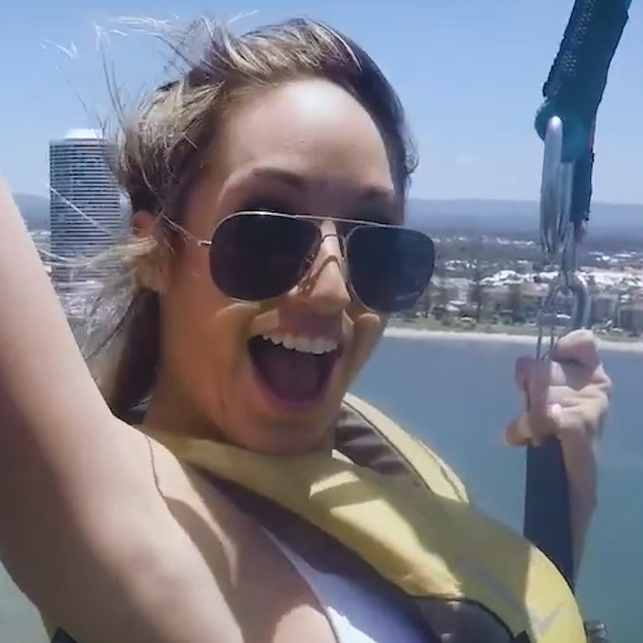 A close up photo of a girl in the sky parasailing