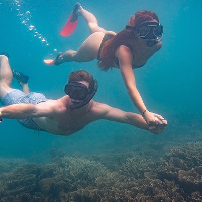 couple snorkelling through the coral reefs in Queensland