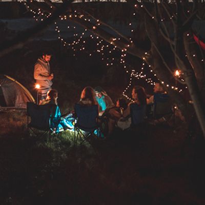 A people in a group at a campground at night with twinkle lights