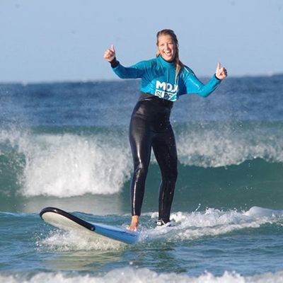 girl giving a thumbs up while surfing at mojo surf camp