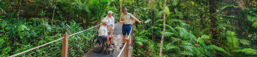 Rainforest guide with man in wheelchair on boardwalk