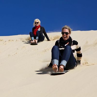 two women sandboarding down the stockton sand dunes