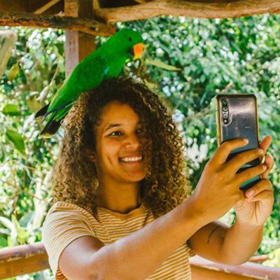 traveller taking a selfie with a king parrot on her head