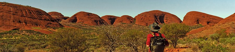 man with backpack looking at the olgas mountains