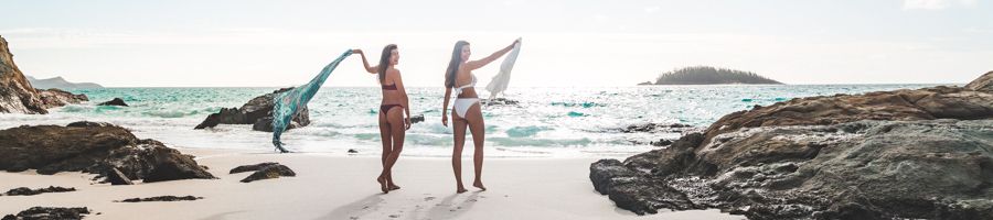 two girls on the beach holding towels in the whitsundays