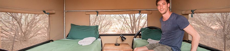 man sitting on campsite bed in the outback