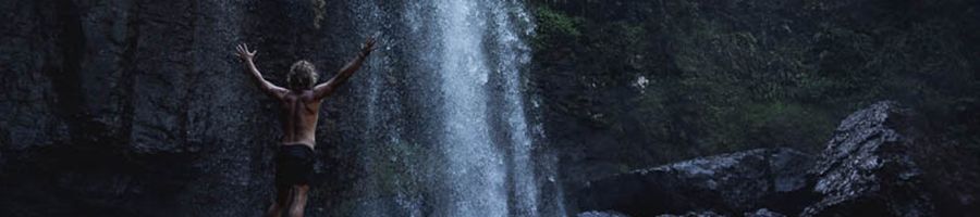 man posing in front of a waterfall in Australia