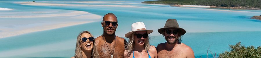 group of four travellers smiling at hill inlet lookout whitsundays