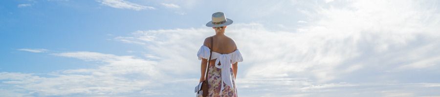 A woman in a sunhat walking along the beach in Noosa, Queensland