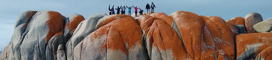 A group of people standing on top of Bay Of Fires