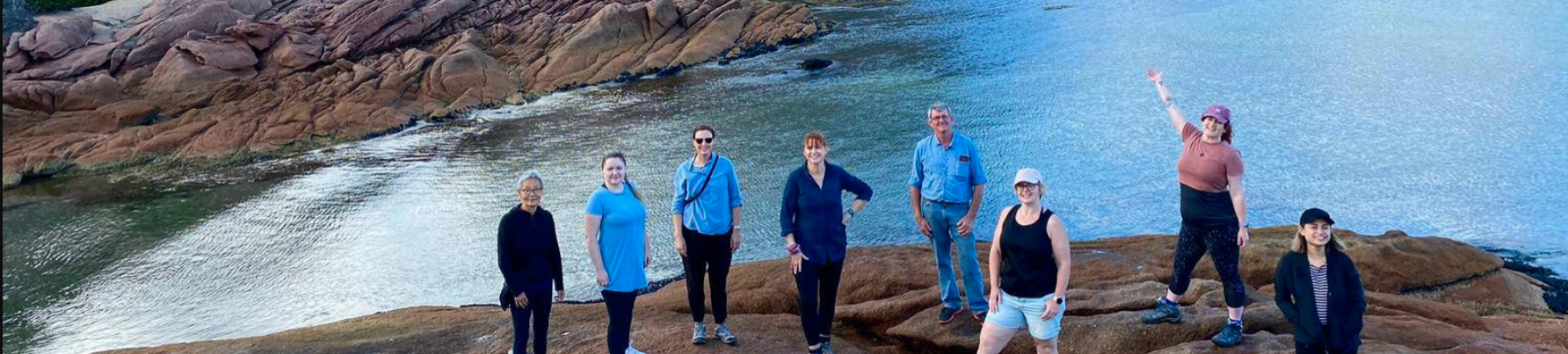 A group of people standing on a rock by a lake