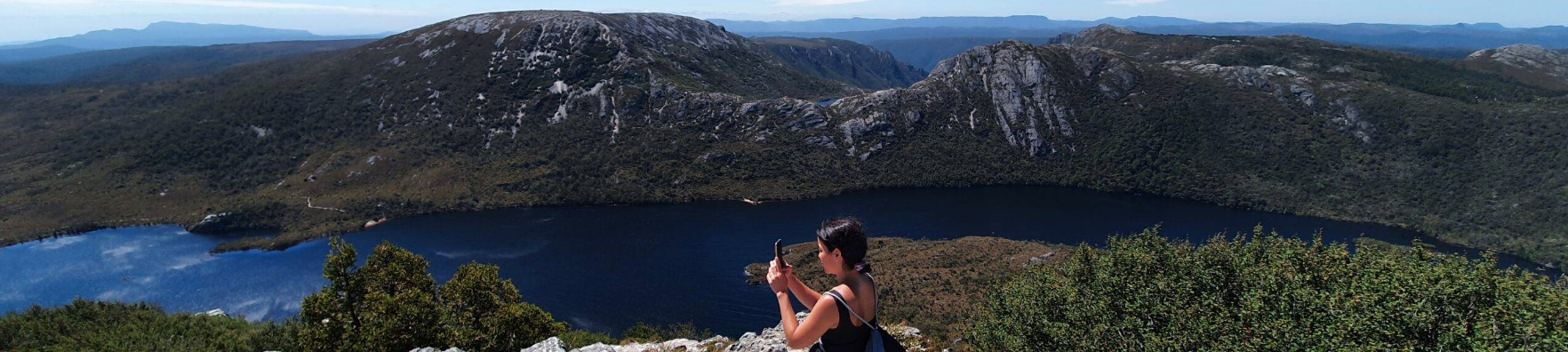 A woman taking a picture on a mountain top