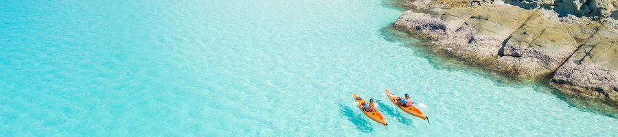 kayakers paddling across bright blue water at whitsunday island