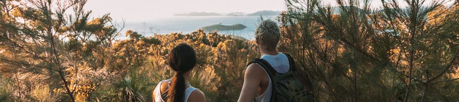 couple hiking in the forest overlooking whitsunday islands