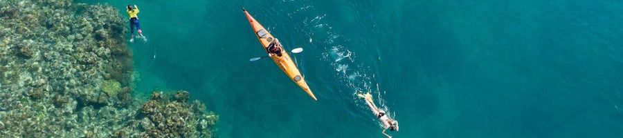 kayak and snorkellers on top of coral reefs in the whitsundays