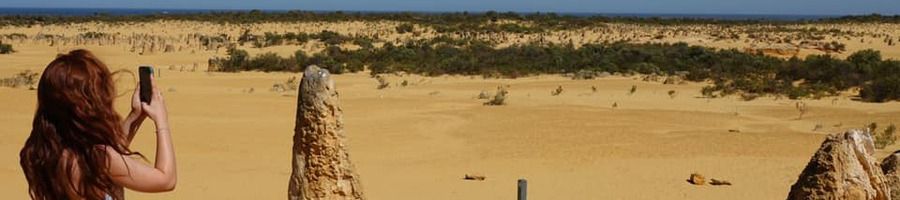 woman taking photo of pinnacles desert in western australia