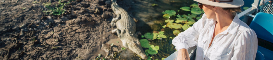 woman on boat observing crocodile on river bank