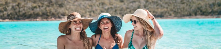 three girls smiling in the water at whitehaven beach