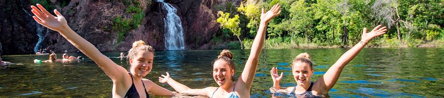 three girls swimming in a waterfall in litchfield national park