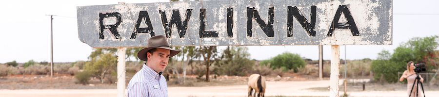 man walking past the sign at rawlinna in the outback