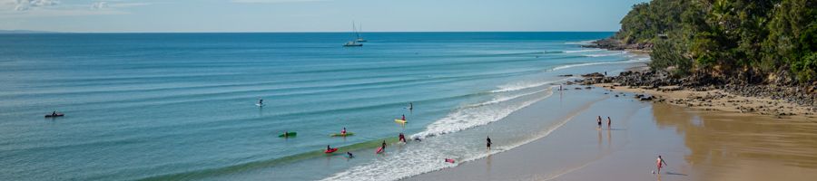 Noosa Main Beach filled with surfers and sunbathers