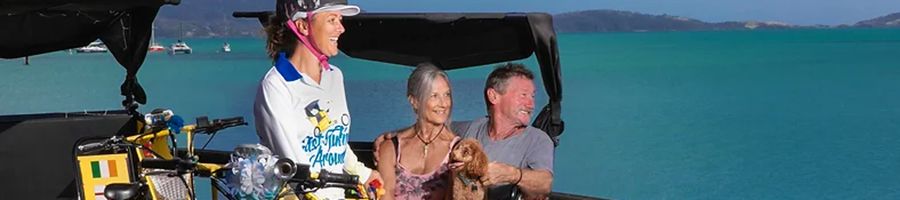 A couple and a dog on a tuk tuk by the water 