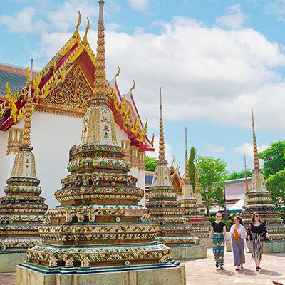 A thai temple with three travellers walking through golden architecture