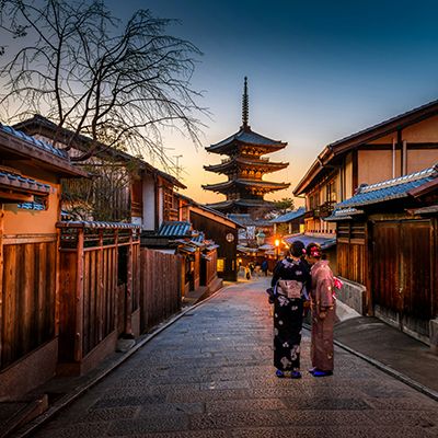 geisha standing in street at night in gion kyoto