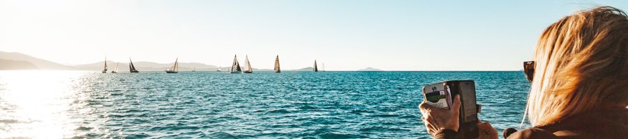 woman taking a photo of sailboats during airlie beach race week