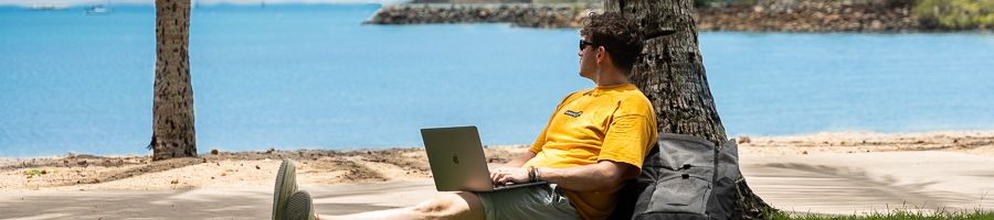 A man in a yellow shirt on the Airlie Esplanade with a computer