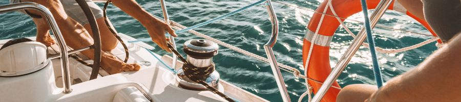 A pair of sailors manning the ropes on a white sailing boat