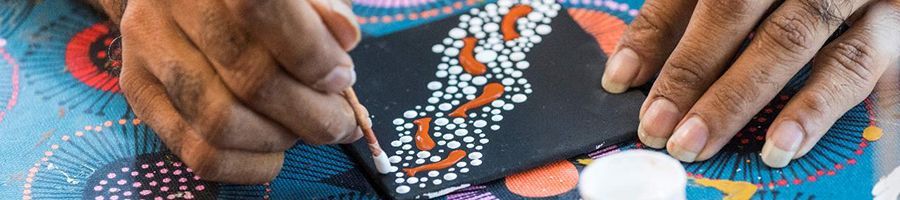 man painting aboriginal artwork in an art class