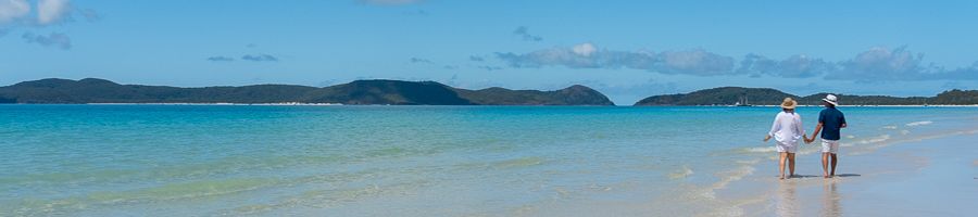 couple walking along the blue water of whitehaven beach