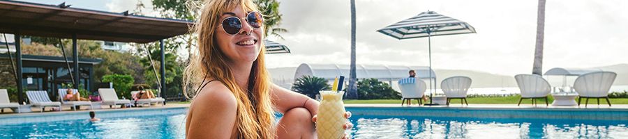 A woman holding a cocktail overlooking the Coral Sea