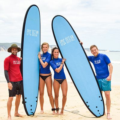 surf teacher and students posing with surfboards