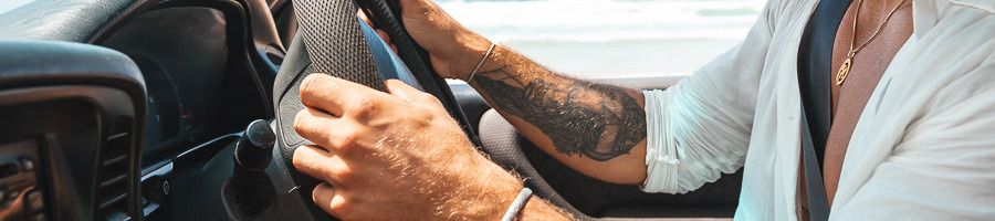 A man's arms holding onto the steering wheel of a 4WD vehicle