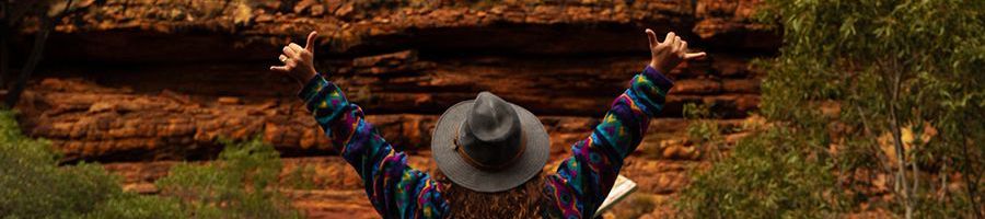 girl with hat posing in front of a red rock wall