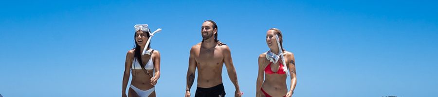 group of three people with snorkel gear on the beach